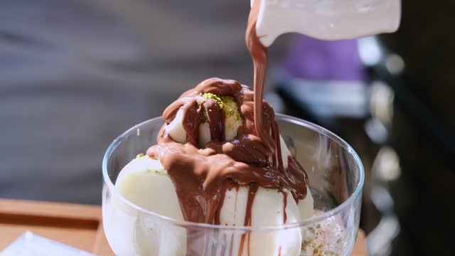 Vanilla ice cream and pistachio particles with chocolate sauce in bowl
