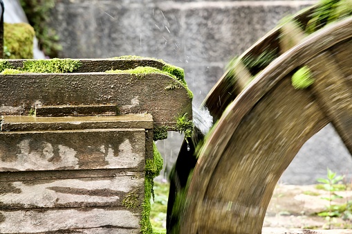 Moss covered water powered wooden wheel at disused mill