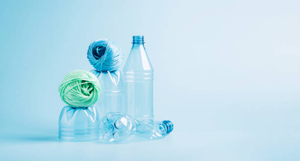 istock Plastic recycling and reuse concept. Empty plastic bottle and polyester fiber synthetic thread on a blue background. 1335269247