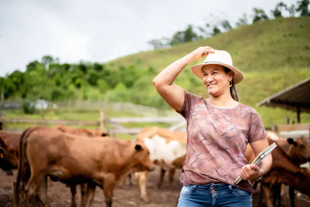 Photo of Smiling female farm manager standing in a corral on a cattle ranch