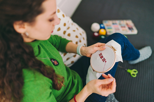 Young woman embroidering at home