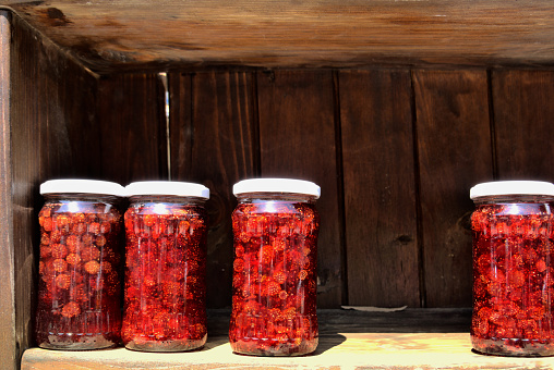 Opening kitchen cabinet with raspberry jam in jars.