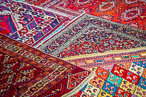 Oriental Turkish Persian rugs displayed at angles on sidewalk in Eurasia.