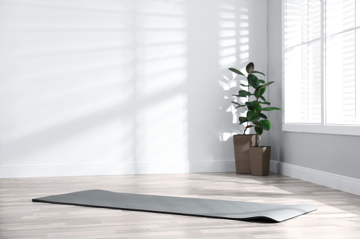Estera de yoga gris desenrollada en el suelo de la habitación photo