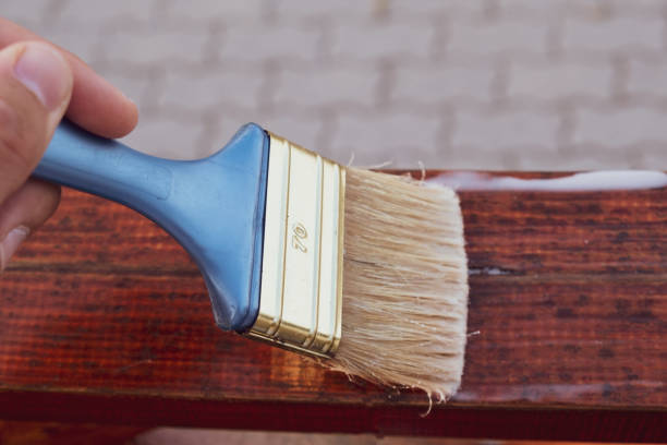 istock Paintbrush in hand applying protective coat on the wooden surface 1335283370