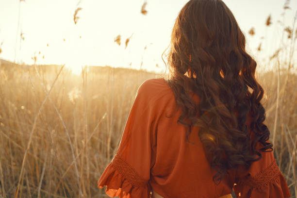 Woman in a summer field. Brunette in a yellow skirt. Girl on a sunset background.