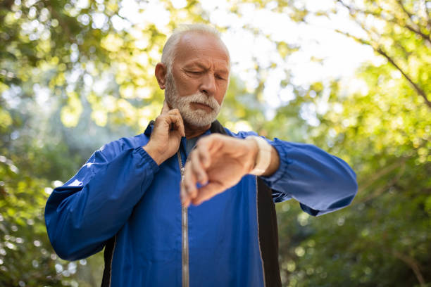 senior man jogging macht eine pause, um den puls zu messen - pulsmessung stock-fotos und bilder