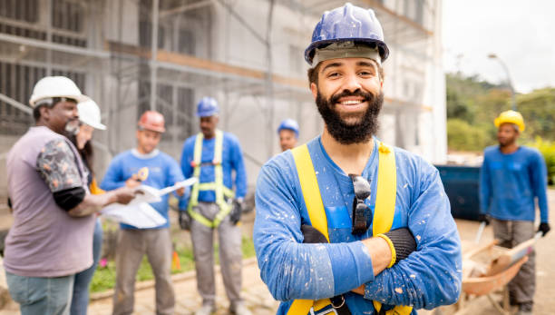 istock Smiling construction worker standing in front of a building site 1335290914