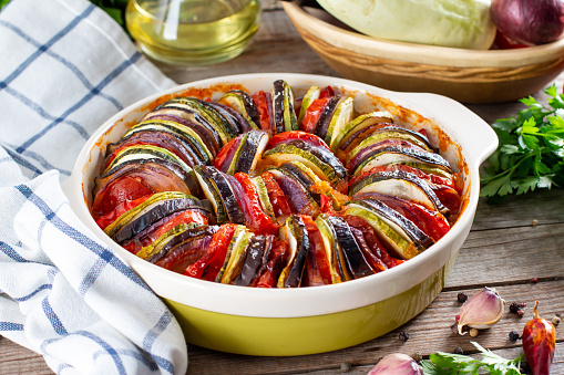 Ratatouille in baking dish on a wooden table. Traditional French Provencal vegetable dish. Dieting, vegan food. Ratatouille casserole. For menu or banner.