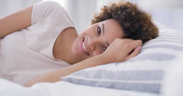 istock Shot of a young woman smiling while lying on her bed 1335291413