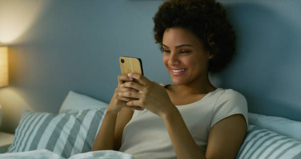 istock Shot of a young woman using her cellphone while lying in her bed at nighttime 1335291430