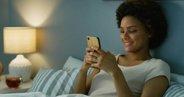 istock Shot of a young woman using her cellphone while lying in her bed at nighttime 1335291433