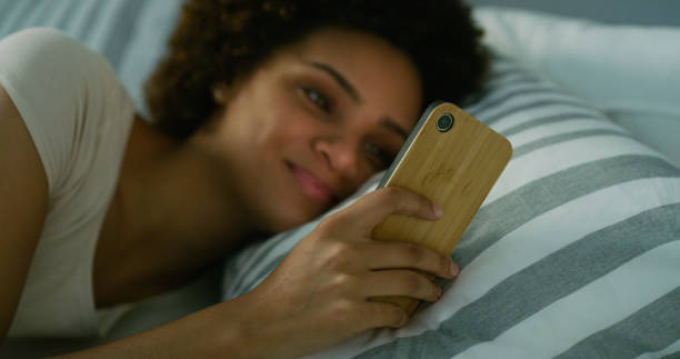 istock Shot of a young woman using her cellphone while lying in her bed at nighttime 1335291447