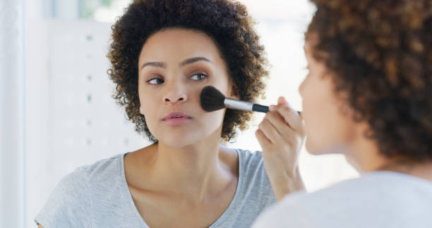 istock Shot of a young woman using a makeup brush on her face while looking into the mirror 1335291451
