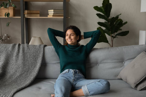 istock Smiling attractive young woman leaning back on cozy couch 1335294903