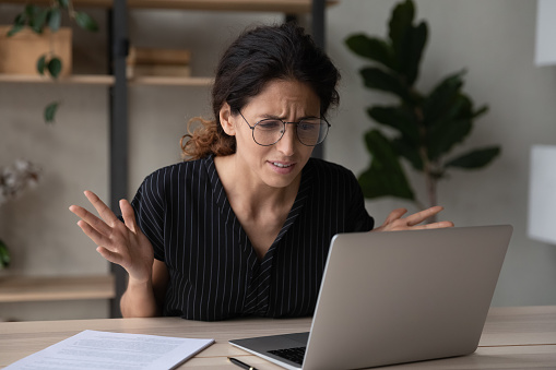 Close up upset businesswoman in glasses having problem with laptop, broken or discharged device, confused unhappy woman looking at computer screen, reading bad news, unexpected debt or spam