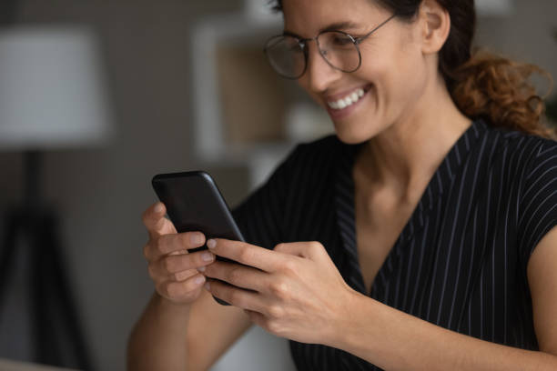 istock Close up smiling woman in glasses using smartphone, browsing apps 1335294979