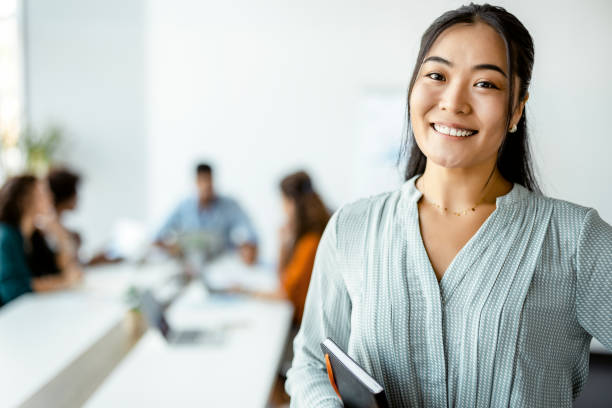 empresaria asiática de pie sonriendo a la cámara - employee fotografías e imágenes de stock