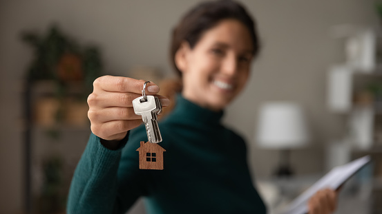 De cerca se centran en las llaves, mujer sonriente agente de bienes raíces que vende apartamento photo