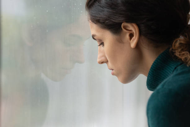 istock Close up pensive depressed woman looking out window alone 1335296848