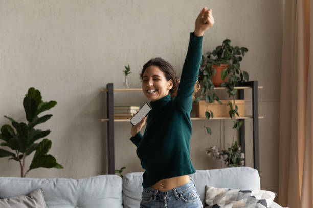 istock Overjoyed woman holding smartphone with blank screen mockup, celebrating success 1335296861