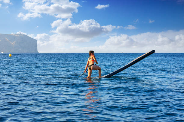 SUP Stand up Surf girl with paddle in a blue ocean sea