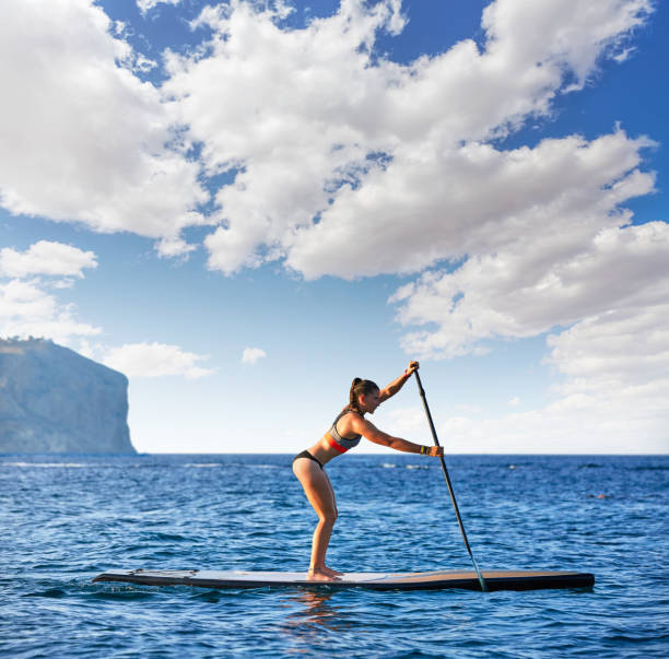 SUP Stand-up Paddleboard. Close-up on legs of a man paddleboarding