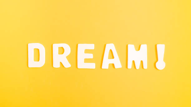 istock Minimalistic flat lay concept with white isolated letters on vivid yellow background. Creative optimism, motivation and dream idea, modern aesthetic aesthetics. 1335301558
