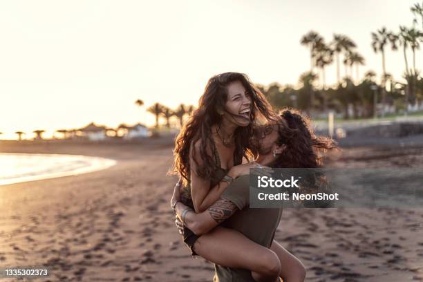 Happy Beautfiul Italian Couple Having Fun Together On The Beach Laughing Sunset Time Stock Photo - Download Image Now