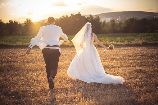Beautiful young bride and groom outside in field