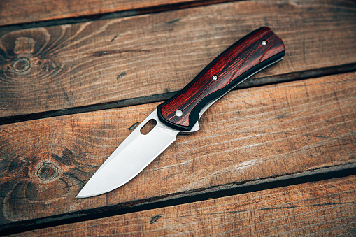 Cuchillo de bolsillo plegable con mango de madera. Un pequeño cuchillo sobre una superficie de madera. photo