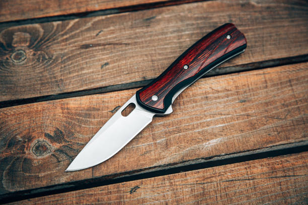 folding pocket knife with wooden handle. a small knife on a wooden surface. - putty knife imagens e fotografias de stock