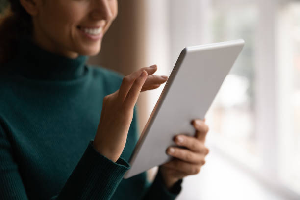 istock Cropped close up smiling woman typing on tablet screen 1335308872