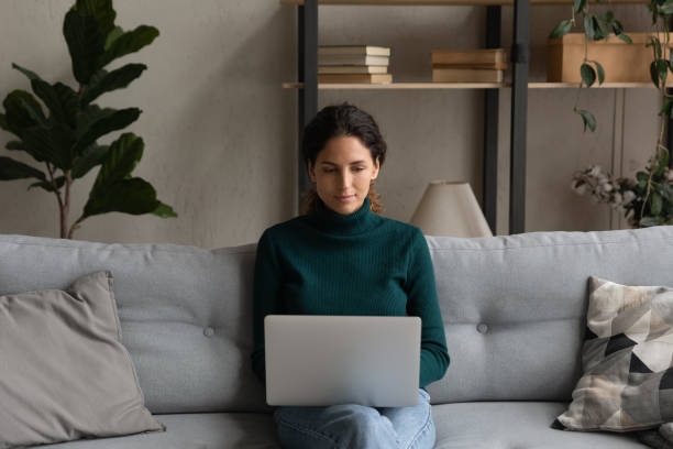 istock Confident young woman with laptop on laps sitting on couch 1335308881