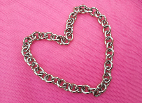 heart-shaped gold metal chain on textured pink cloth surface