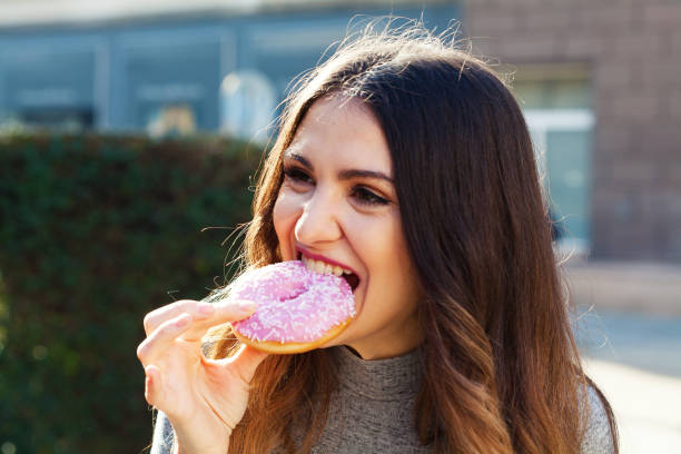 istock Young woman eating a donut 1335310488