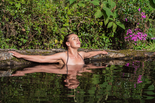 40-year-old Latin woman dressed in a bathing suit dives in the middle of a lake in nature