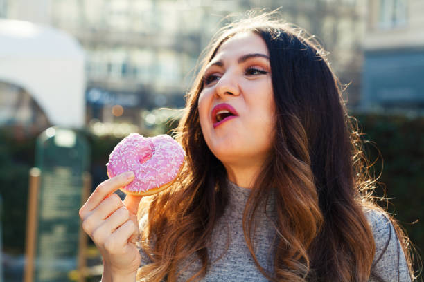istock Young woman eating a donut 1335317255