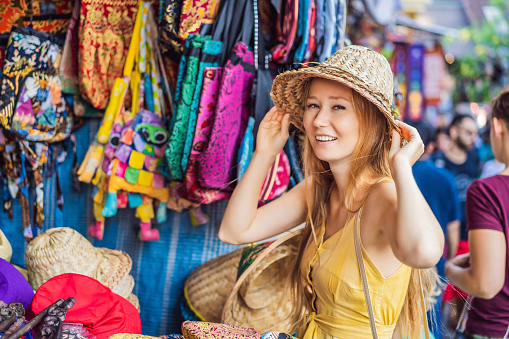 Woman traveler choose souvenirs in the market at Ubud in Bali, Indonesia.
