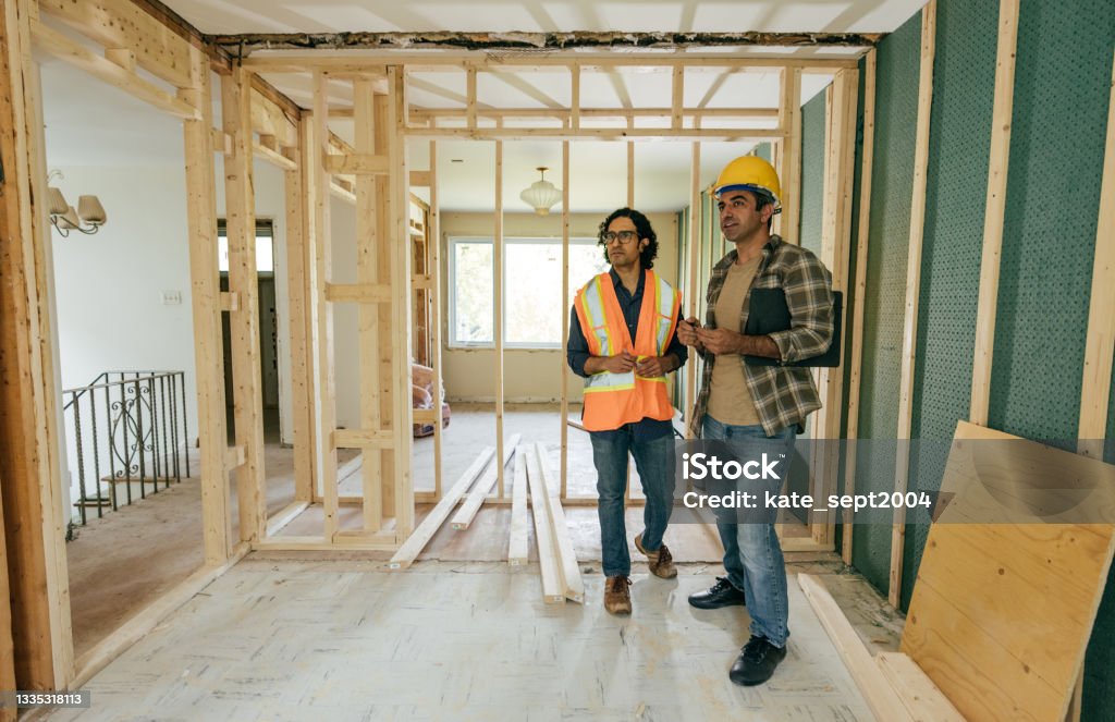 Renovation or Addition Advantages Construction worker is showing to project manager completed design on construction site. Home Improvement Stock Photo