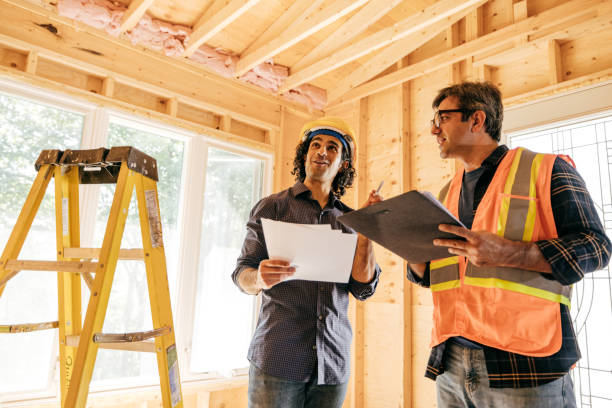 Checking Our Progress Two engineers looking over the blueprints for a home remodel they are working on. general contractor stock pictures, royalty-free photos & images