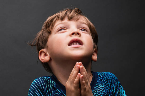 istock Little boy looking up praying 1335318795