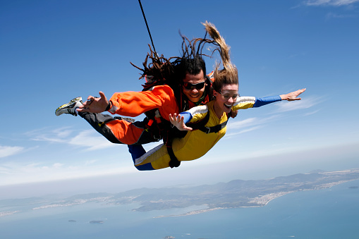 April 19, 2009. Porto Belo, Santa Catarina, Brazil. An instructor with dreadlocks and a female student jump tandem parachutes, and in the background the island of Florianópolis.