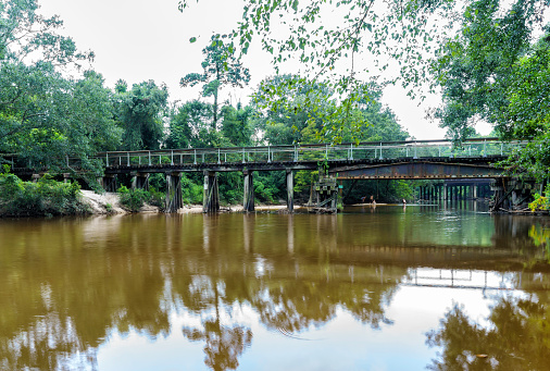 Calm water of the Bogue Falaya River flows underneath an old historic railroad trestle, now part of the Rails To Trails project of Saint Tammany Parish