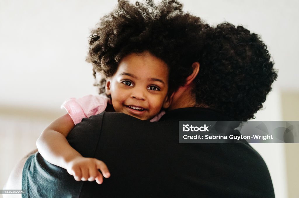 Father & Daughter A mixed race father holds his black daughter while she smiles looking towards the camera. Harmony Stock Photo