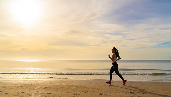 Women running on the beach at morning with beautiful sunrise