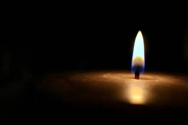 Photo of Isolated glowing candle on black background - stock photo