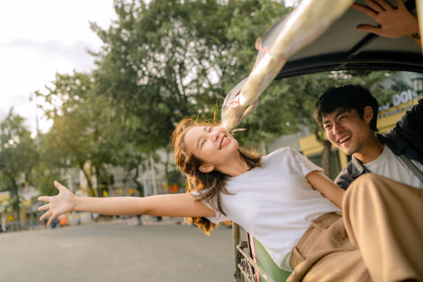 Good-humored couples enjoy memorable moments together in a tuk-tuk. Young Asian couple spends a day in a car in the Bangkok city on vacation. asian stock pictures, royalty-free photos & images