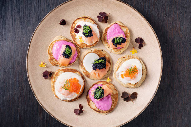 Assorted Blinis With Prawns, Smoked Samon and Caviar. Blinis made with; flour, buckwheat flour, egg yolks, yeast, milk and egg whites. You can create your own recipe but  here shown with; beetroot infused creme fraiche, smoked salmon, prawns, caviar of course, topped with dill. Colour, horizontal format with some copy space. oxalis acetosella flowers stock pictures, royalty-free photos & images