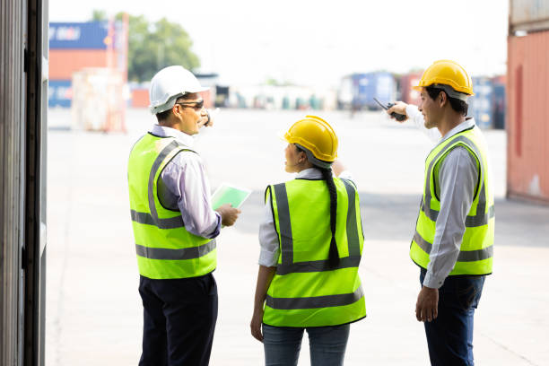 back view shot factory workers or engineers talking and planing for a job in containers warehouse storage